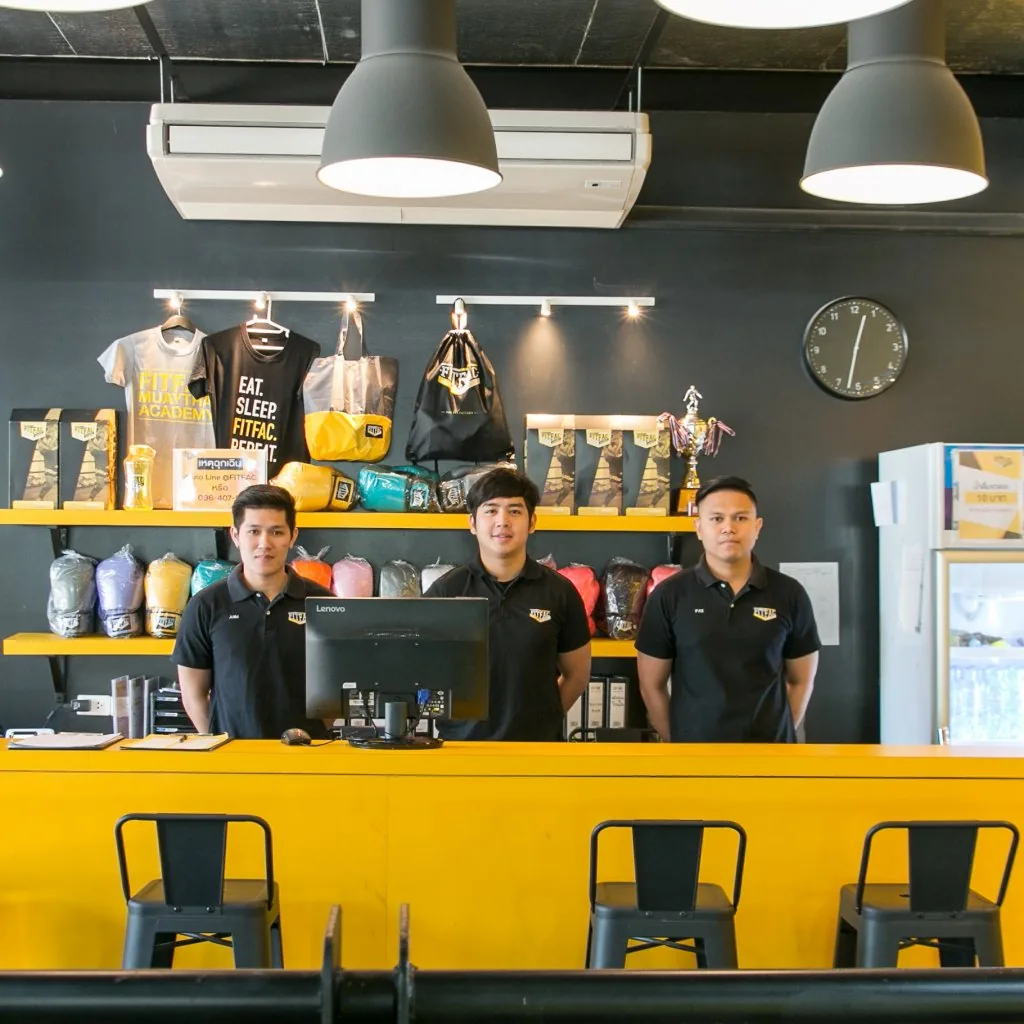พนักงานสามคนที่เคาน์เตอร์ต้อนรับใต้โคมไฟแขวน — FITFAC สาขาราชพฤกษ์