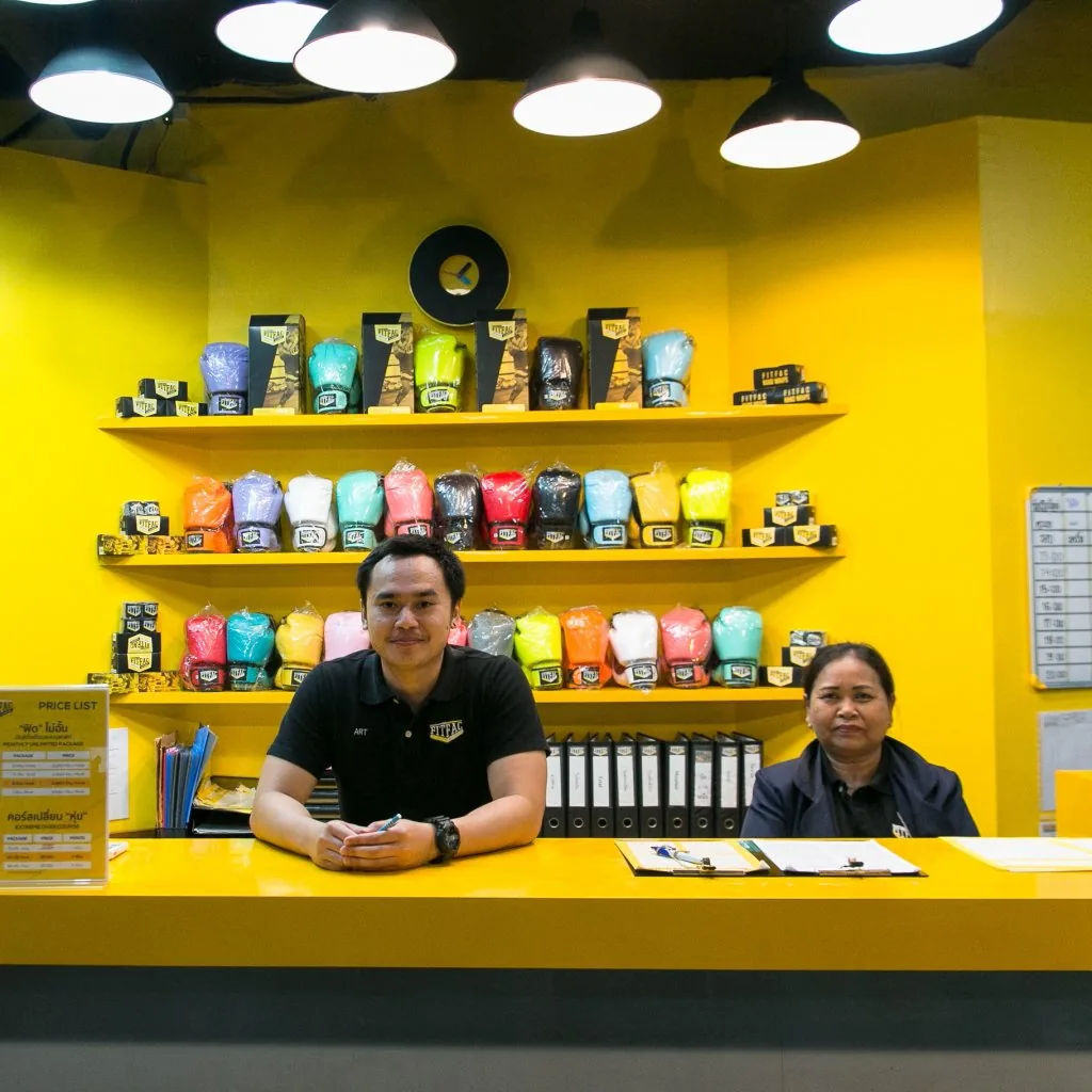 พนักงานสองคนที่เคาน์เตอร์ หน้าชั้นวางนวม — FITFAC สาขาศรีนครินทร์
