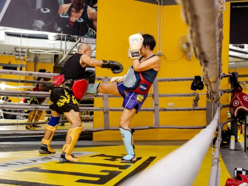 นักเรียนสองคนใส่สนับแข้งซ้อมเตะบนเวทีมวย